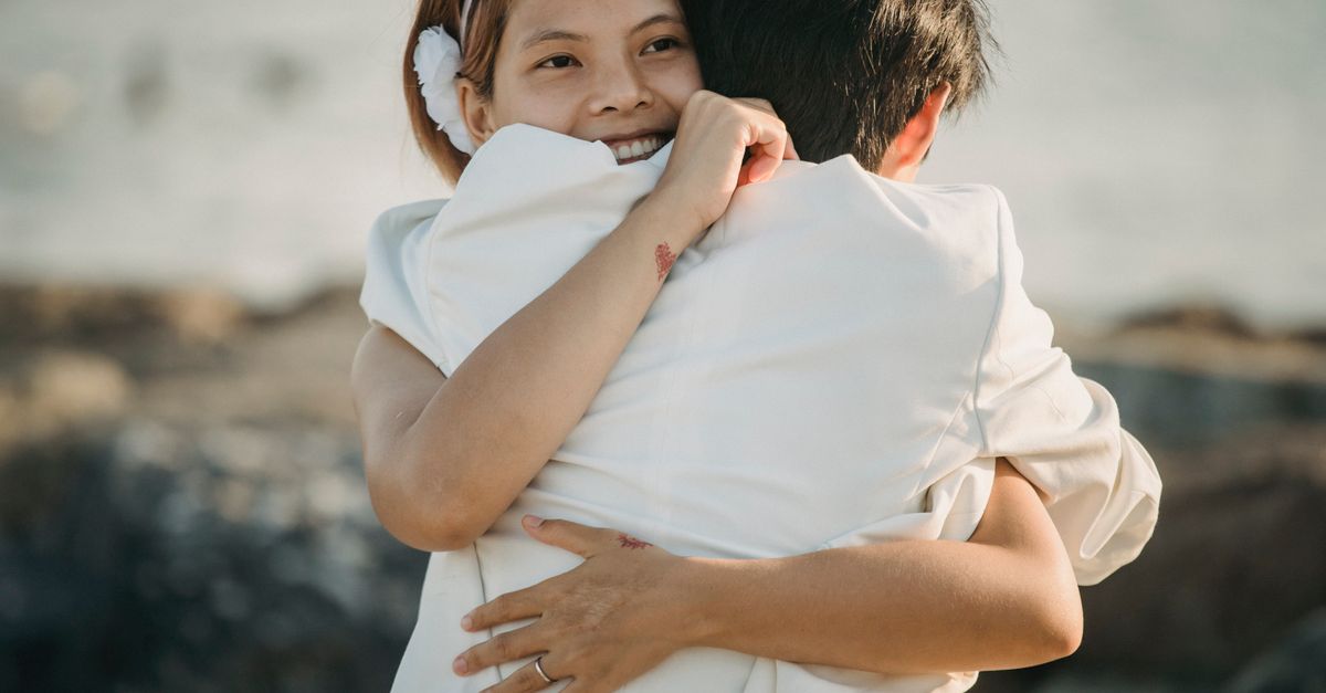 A couple shares a warm hug by the seaside, evoking love and romance.